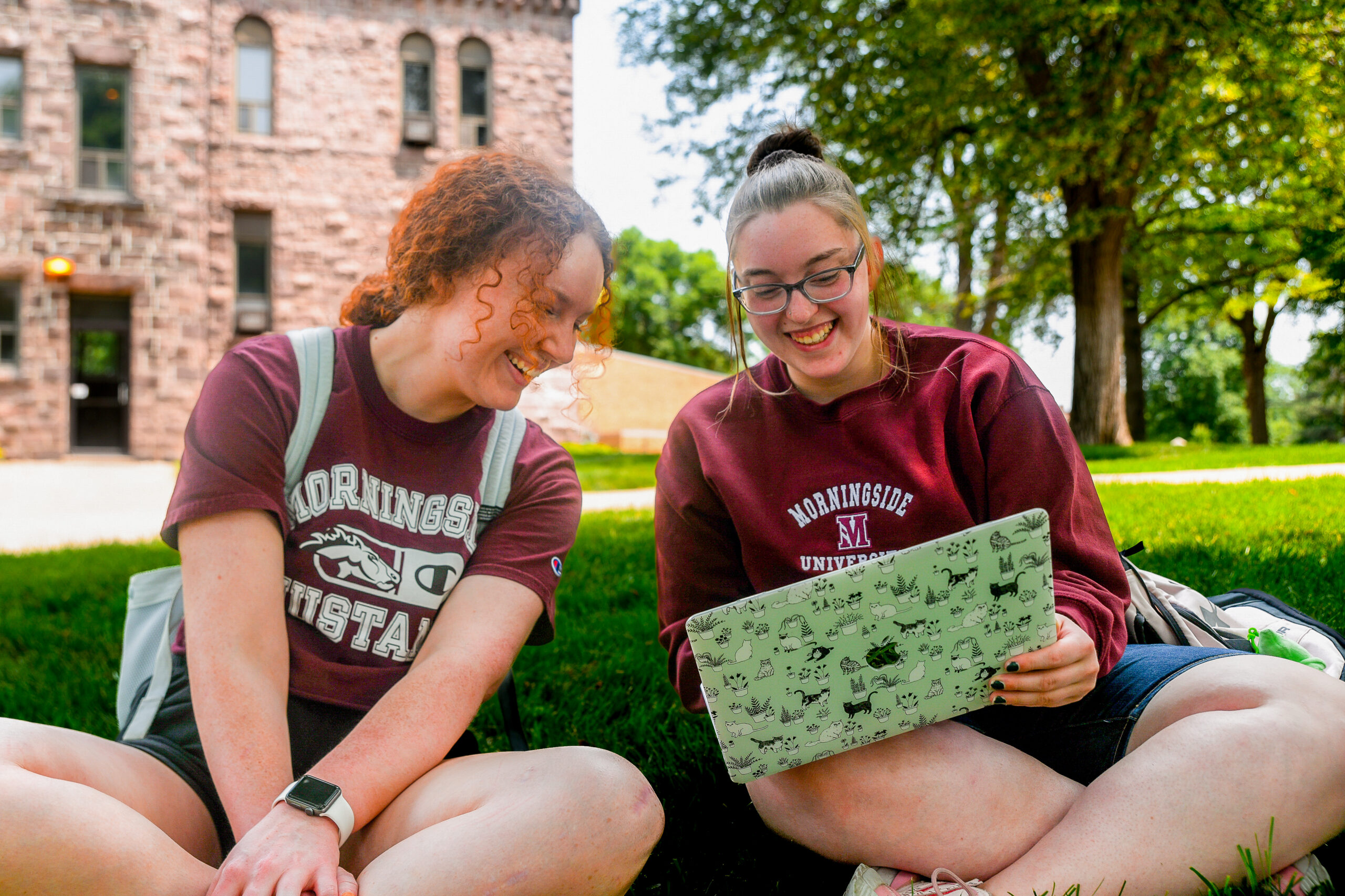 students looking at a computer on a nice day.