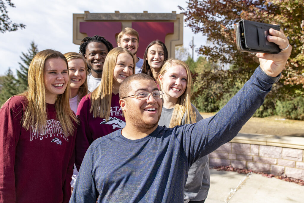 A group of students taking a photo together in front of a big letter M