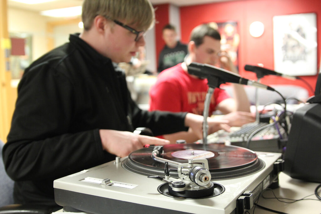 A student with a sound board, record player, and microphone