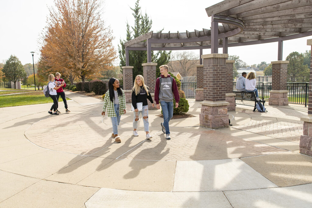 Three students walking across a round, paved area.