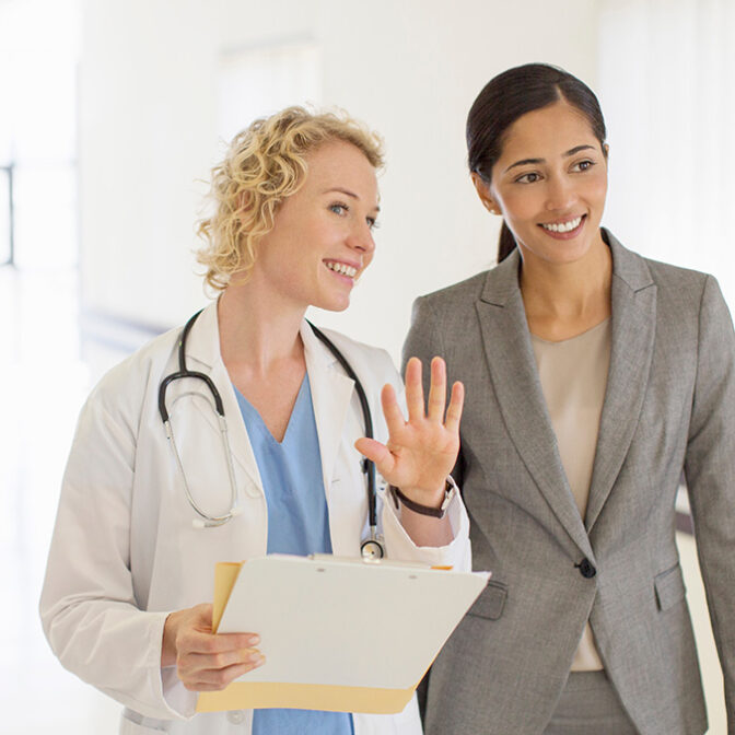 Doctor and businesswoman talking in hospital corridor