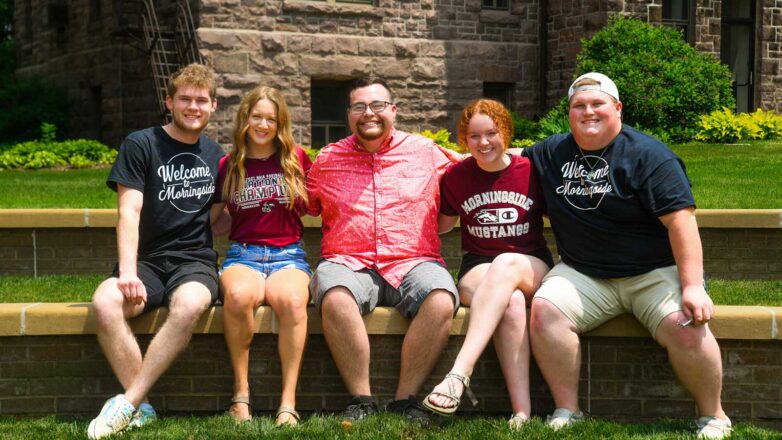 Five Students Sitting On A Bend Outside Charles City Hall