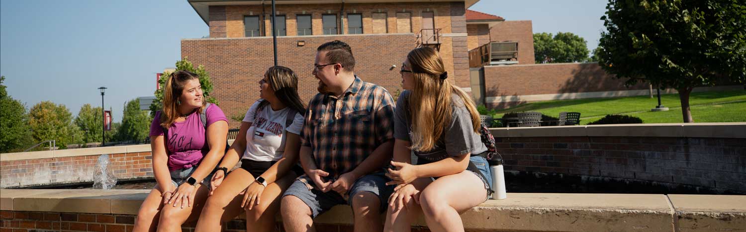 Four Students Sitting By Fountain