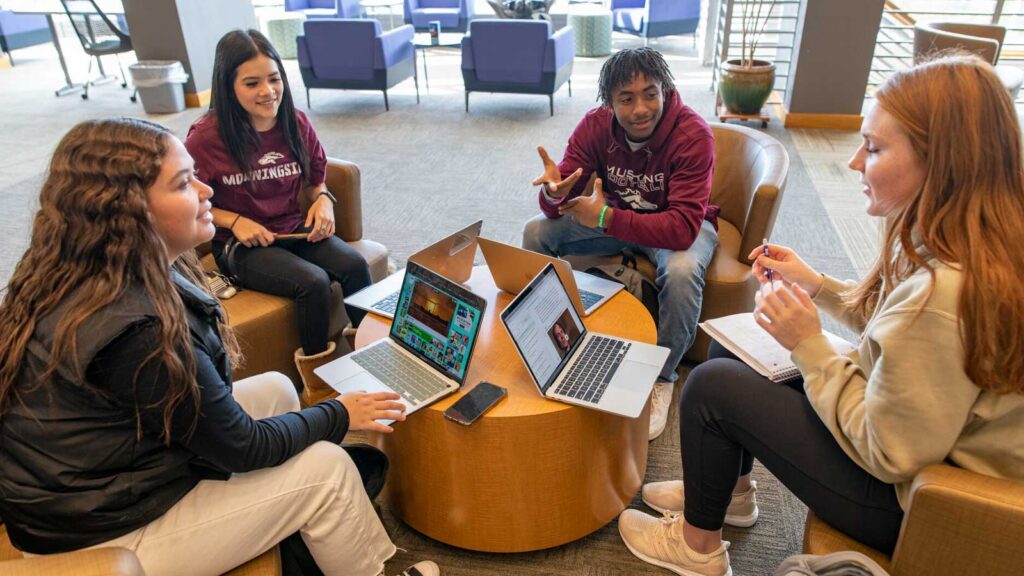 Four Students With Laptops Sitting On Stools