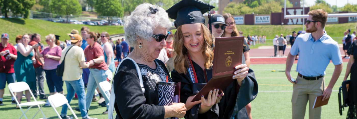 graduate showing diploma to grandmother at commencement