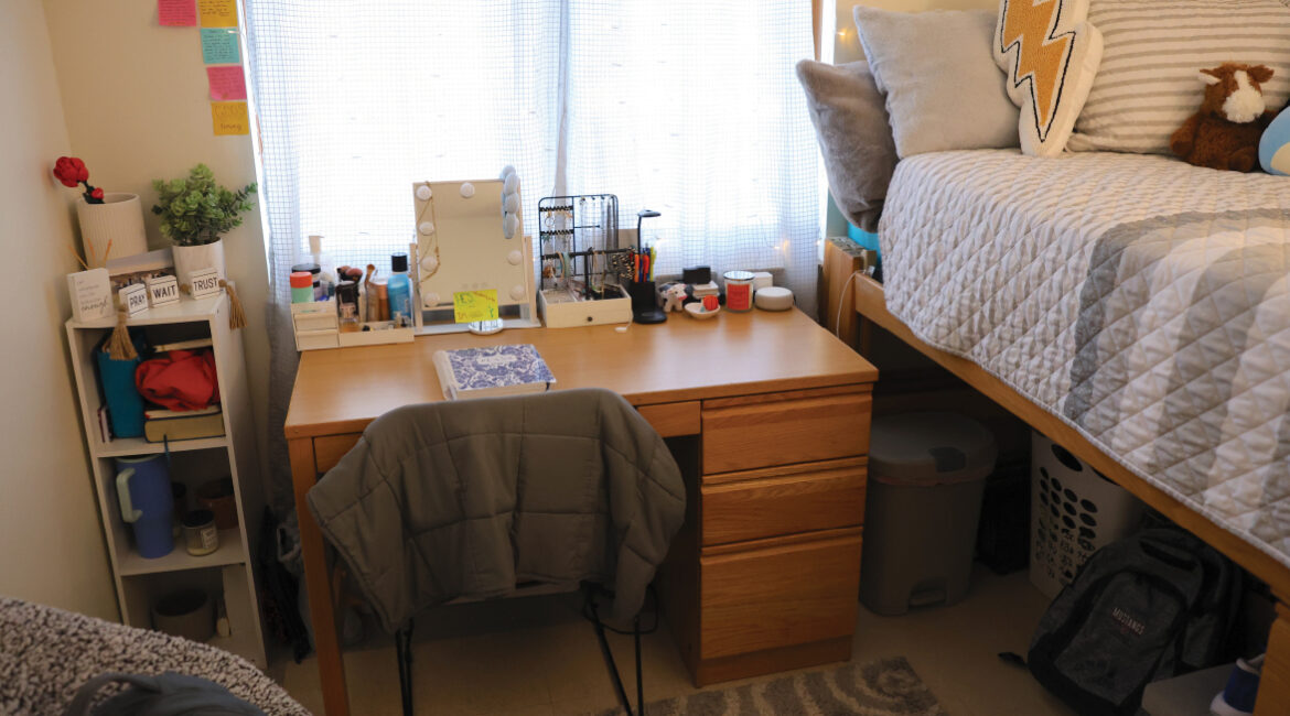 Lags apartment desk close up with bed to the right side.