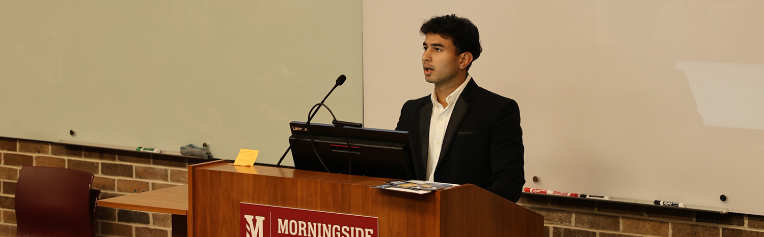 A student speaking at the podium in front of an auditorium