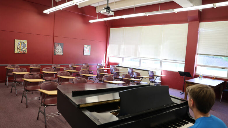 Male Student In Classroom Playing Piano