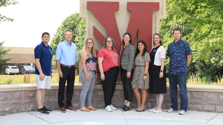 New Faculty Standing In Front Of 'M'