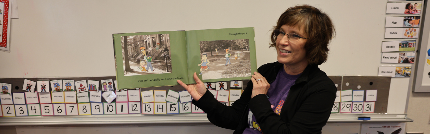 A teacher holding up a picture book in front of a classroom