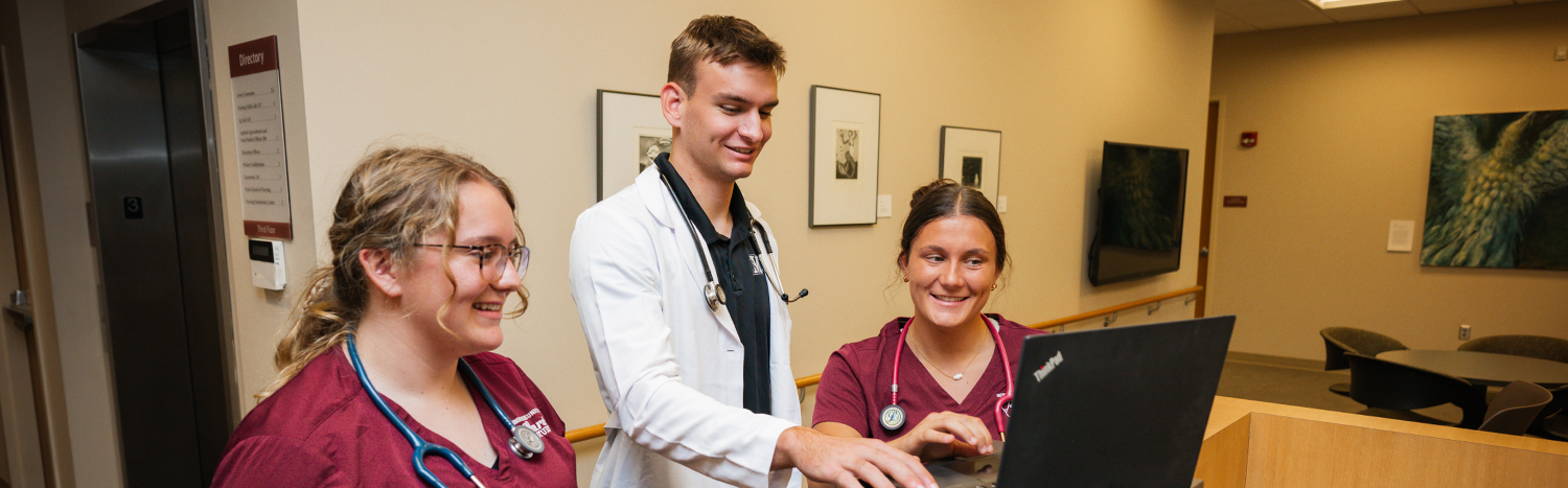Nursing students gathered around a laptop