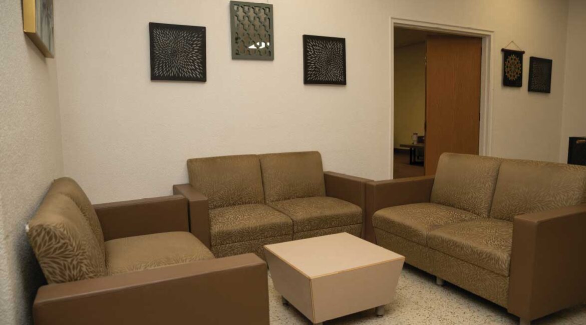 A lounge in Roadman Hall. 3 loveseats surrounding a small coffee table. 