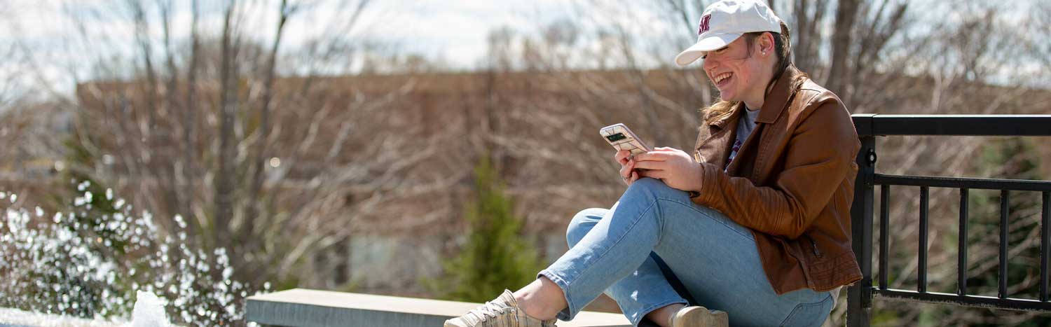 Student Sitting On Fountain With Phone