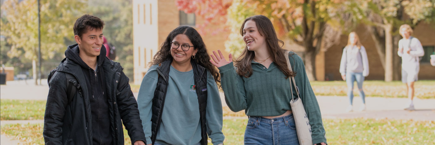 three students walking campus in the fall