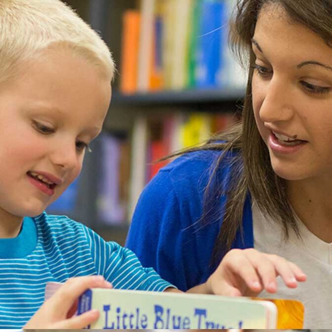 Teacher With Elementary Kid With Book