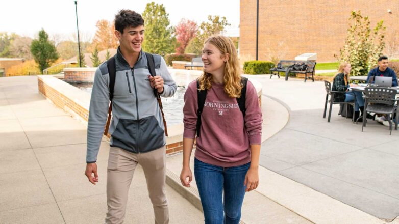 Two Students Walking By Fountain