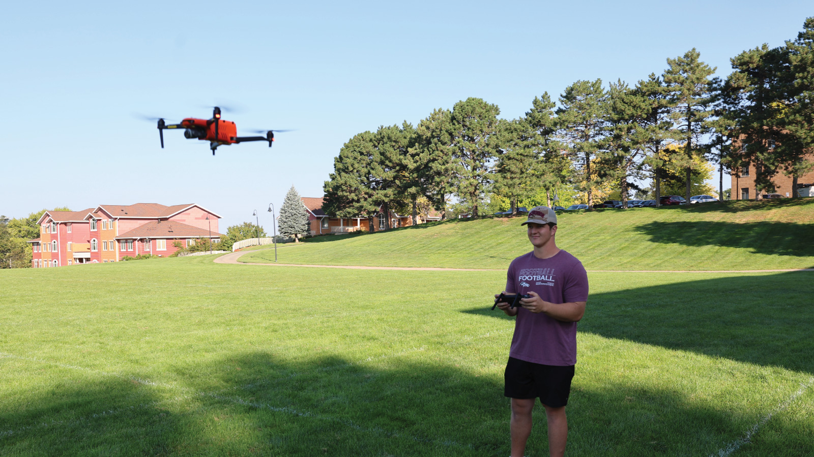 Student flying a drone in an open field