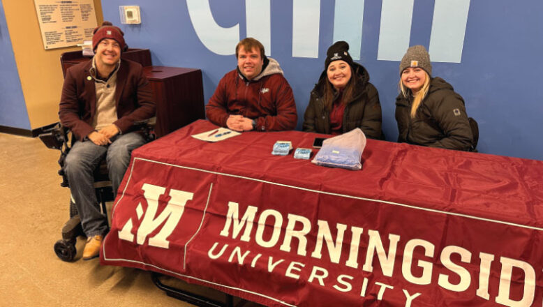 4 alumni sitting at table with Morningside banner