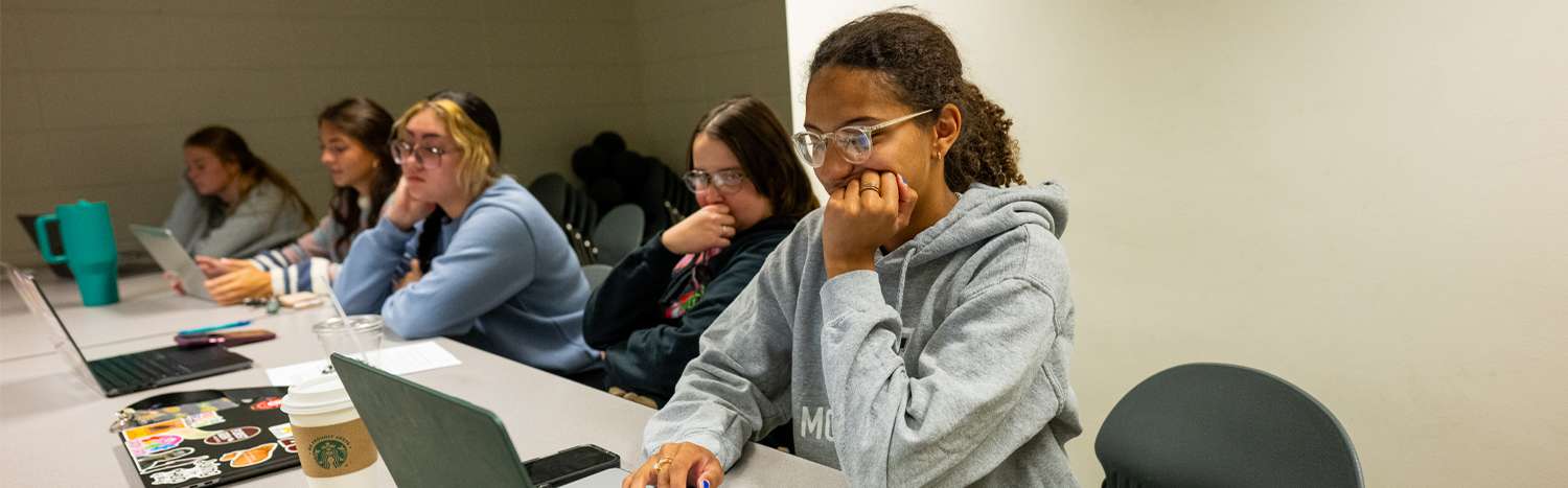 Students sitting in a classroom working on their laptops