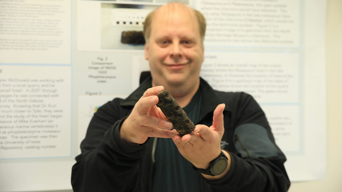 Kurt Spearing is holding the mosasaur fossil discovered by a community member.