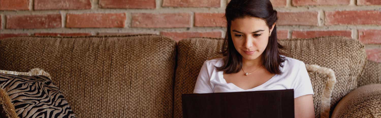 woman sitting on couch studying on her computer