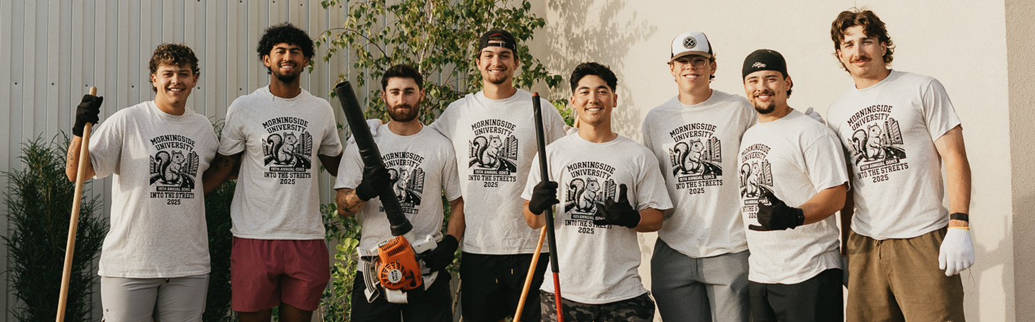 Eight male students smiling for a photo while volunteering during Into the Streets.