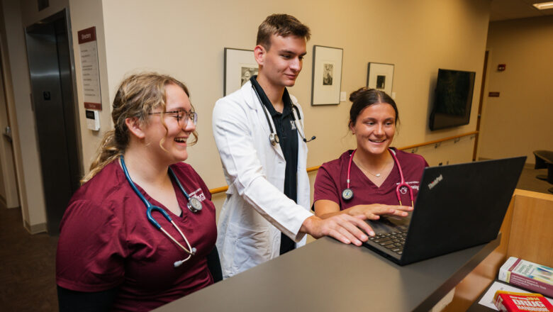 Nursing students and instructor gathered around a laptop