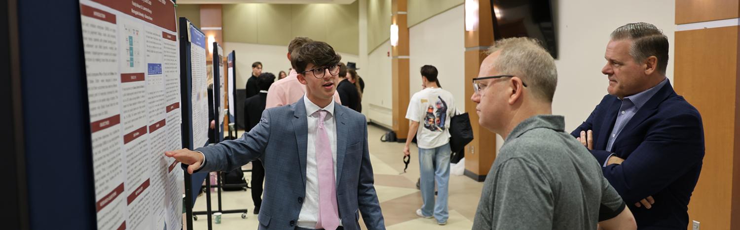Student presenting his poster at a research symposium