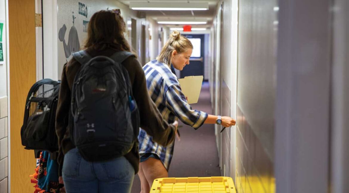 A female student unlocking her door in Roadman hall with another friend. 