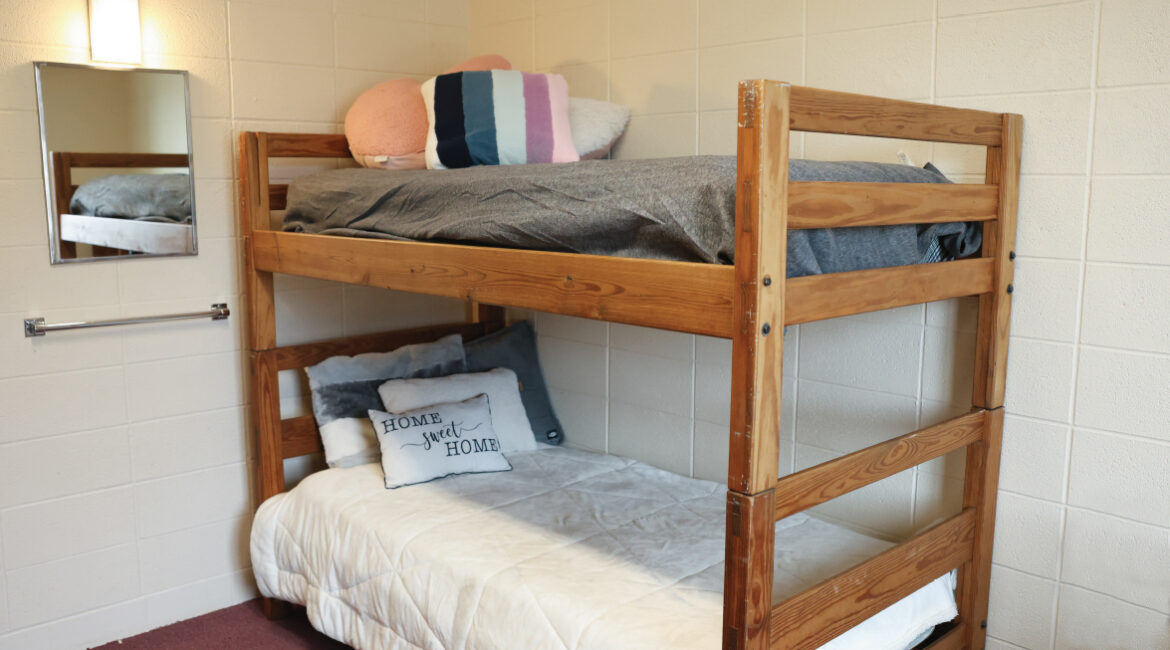 Bunk beds in a room in the Plex. A mirror hanging on the wall. 