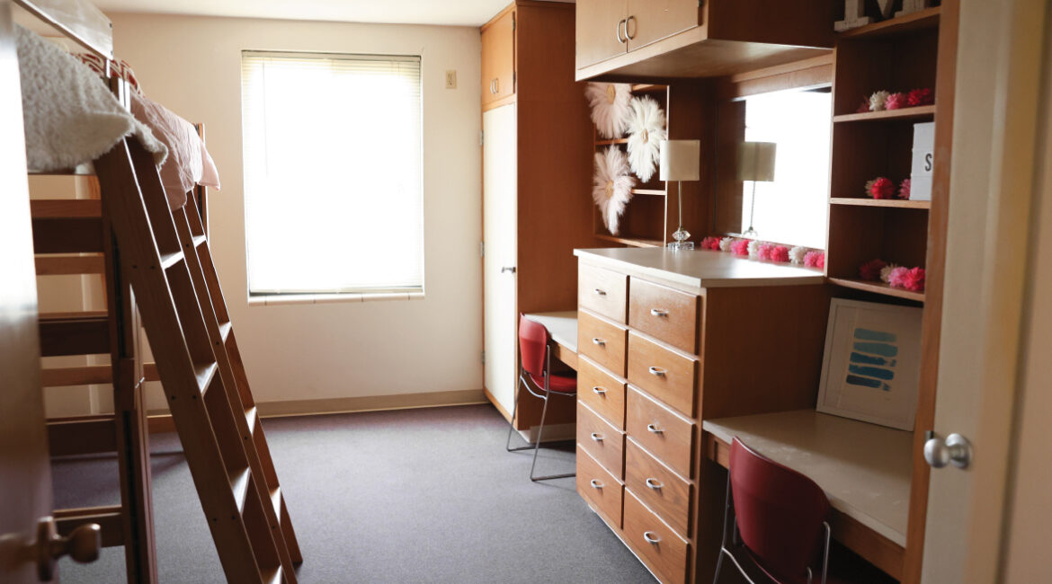 Room in Roadman Hall. Two lofted beds on the left and two built in closets, desks, and dressers on the right.