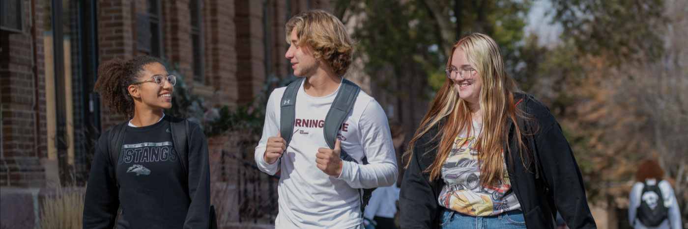 three students walking in front of Lewis Hall