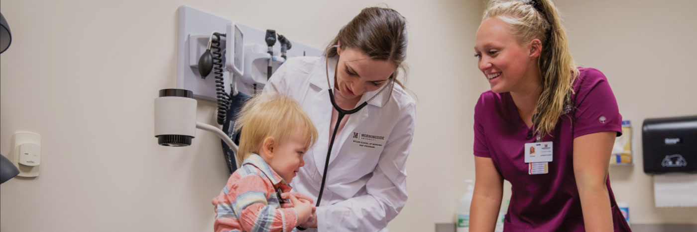 Nurse practitioner and nursing student in a clinic room examining a toddler.