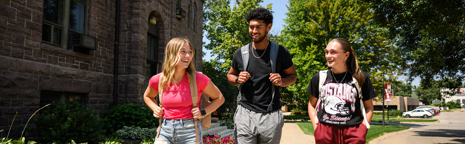 Three students walking outside through a college campus