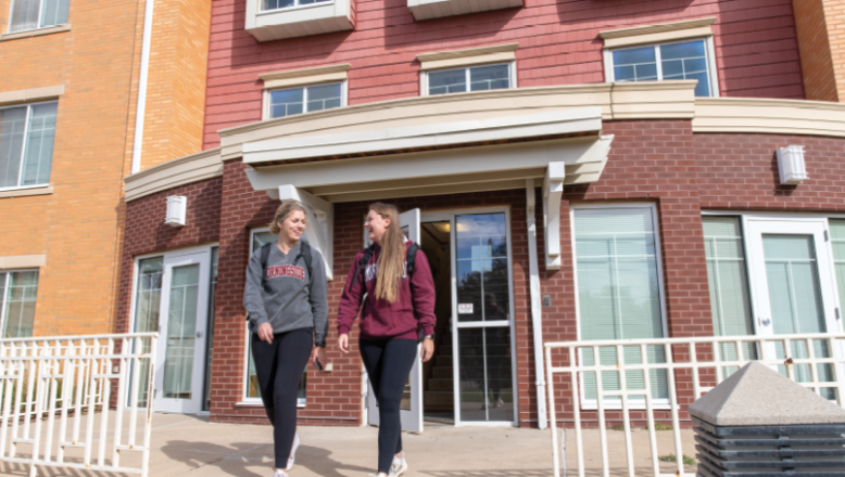 two students walking outside campus apartment