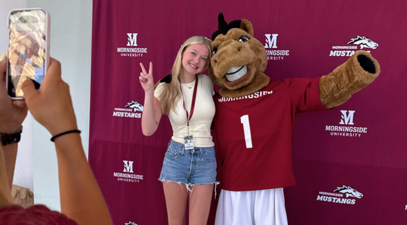 Student posing for a picture with Monte.